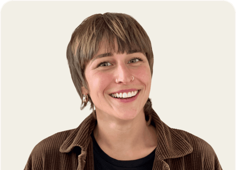 Smiling woman with short brown hair and bangs wearing a brown corduroy jacket.