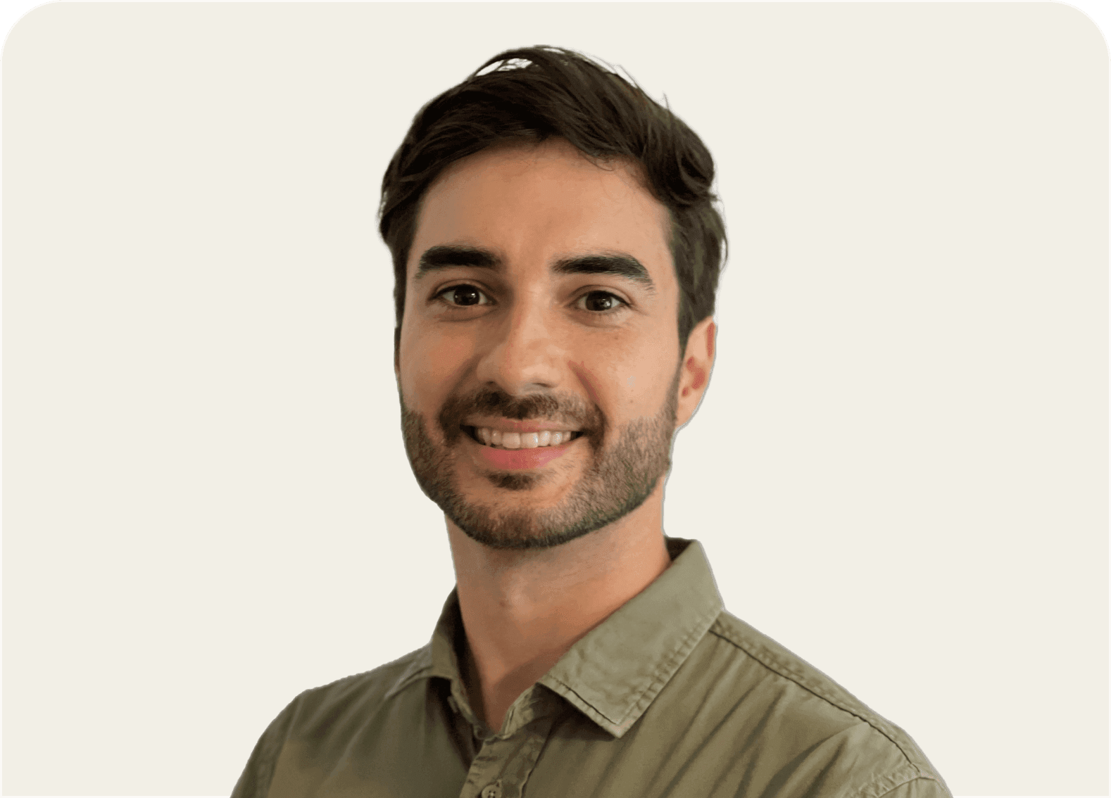 A smiling young man with short dark hair and a beard wearing a green shirt.