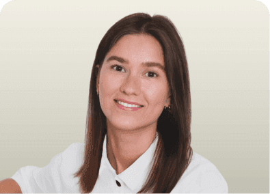 A smiling young woman with long brown hair wearing a white collared shirt.